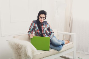 Bir dizüstü bilgisayar ile beyaz kanepe üzerinde genç kız.