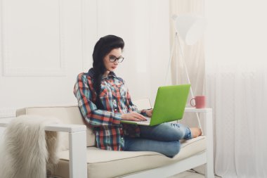 Bir dizüstü bilgisayar ile beyaz kanepe üzerinde genç kız.