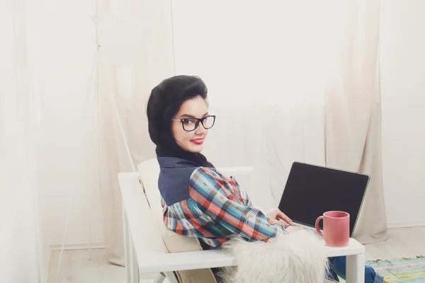 Giovane ragazza sul divano bianco con un computer portatile . — Foto Stock