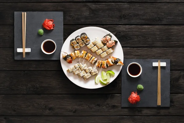 Set Sushi Maki und Rollen aus rustikalem schwarzem Holz. — Stockfoto