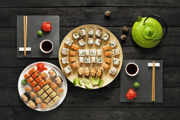 Set sushi maki en rollen in zwart rustiek hout. — Stockfoto