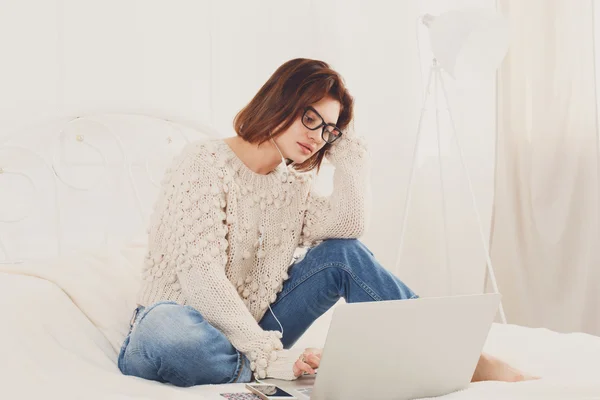 Junge Frau liest vom Laptop im Bett, hoher Schlüssel — Stockfoto