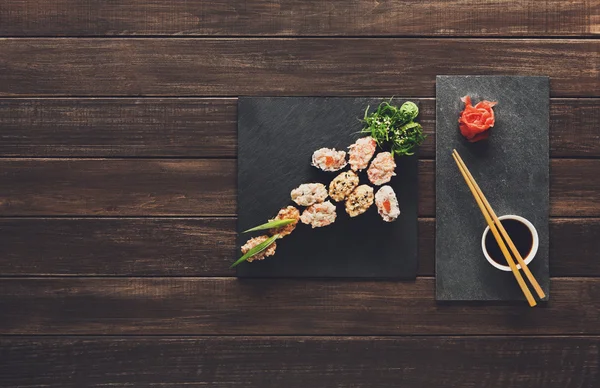 Conjunto de sushi maki e rolos em madeira rústica preta . — Fotografia de Stock