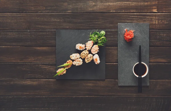 Uppsättning av sushi maki och rullar på svart rustikt trä. — Stockfoto