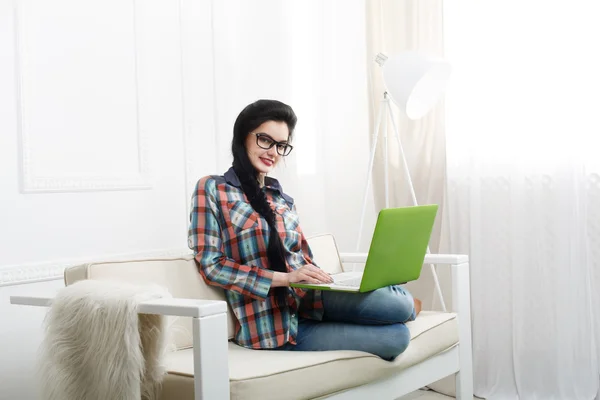 Jeune fille sur canapé blanc avec un ordinateur portable . — Photo