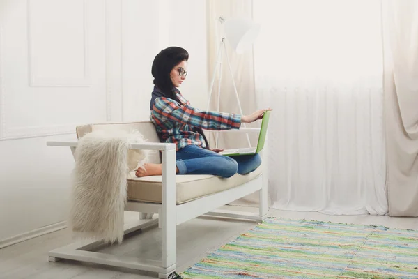 Jeune fille sur canapé blanc avec un ordinateur portable . — Photo