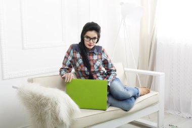 Bir dizüstü bilgisayar ile beyaz kanepe üzerinde genç kız.