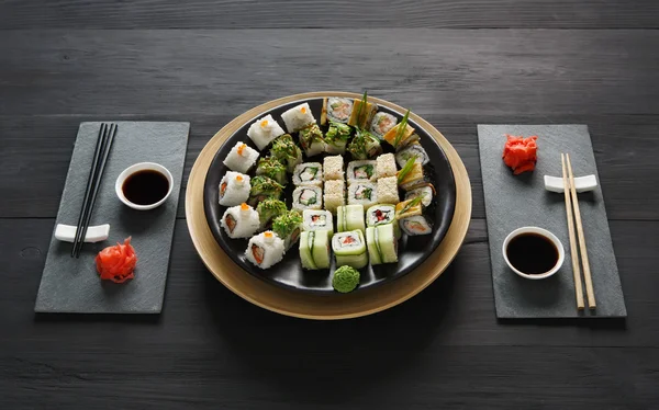 Uppsättning av sushi maki och rullar på svart rustikt trä. — Stockfoto