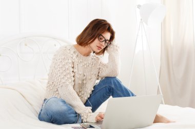 Genç kadın yatakta, yüksek anahtar dizüstü bilgisayar okur