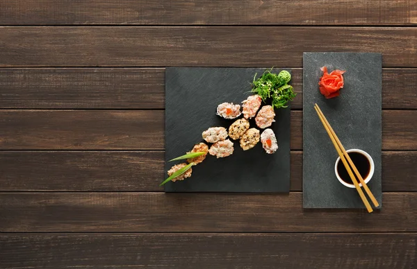 Set sushi maki en rollen in zwart rustiek hout. — Stockfoto