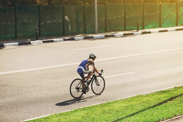 Mujer ciclista monta una bicicleta de carreras en la carretera —  Fotos de Stock