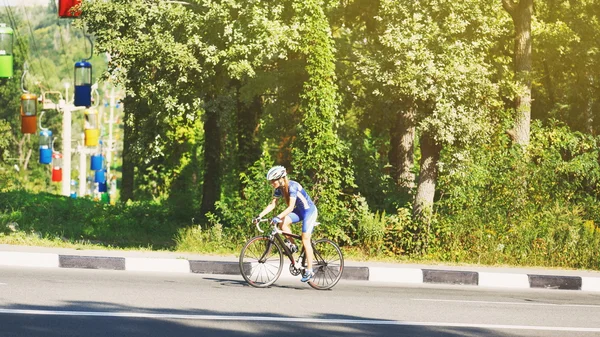 Mujer ciclista monta una bicicleta de carreras en la carretera —  Fotos de Stock