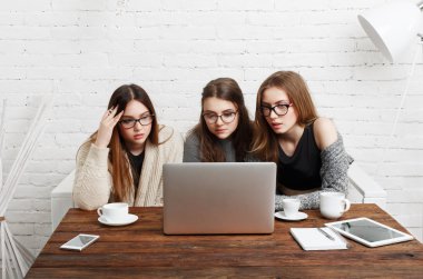 Dizüstü bilgisayar ile üç genç kadın arkadaş.