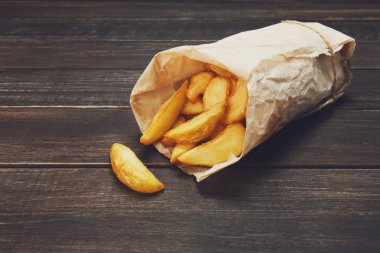 Tasty potato wedges wrapped for takeaway at wood