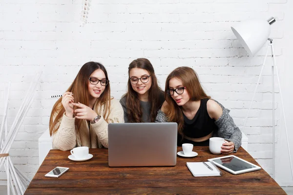 Portret van drie lachen vriendinnen met laptop. — Stockfoto