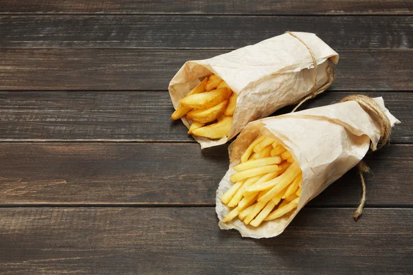 Papas fritas y cuñas de patata envueltas para llevar en madera — Foto de Stock