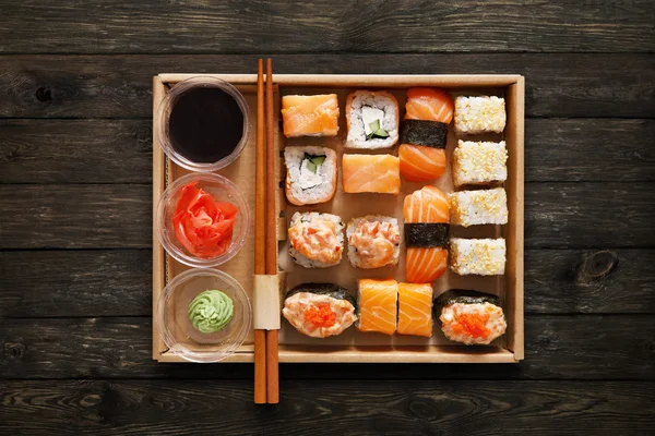 Conjunto de sushi maki y rollos en caja sobre madera . — Foto de Stock