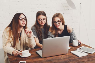 Dizüstü bilgisayar ile üç genç kadın arkadaş.
