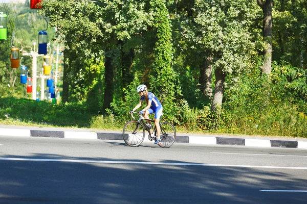 Ciclista fêmea monta uma bicicleta de corrida na estrada — Fotografia de Stock