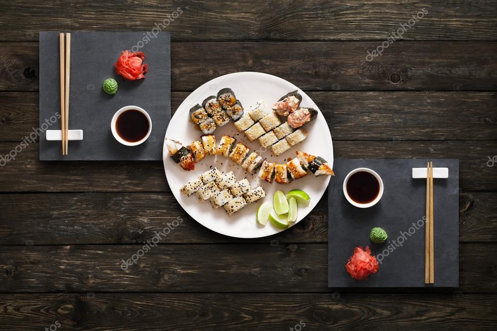 Set sushi maki dan gulungan di kayu pedesaan hitam 