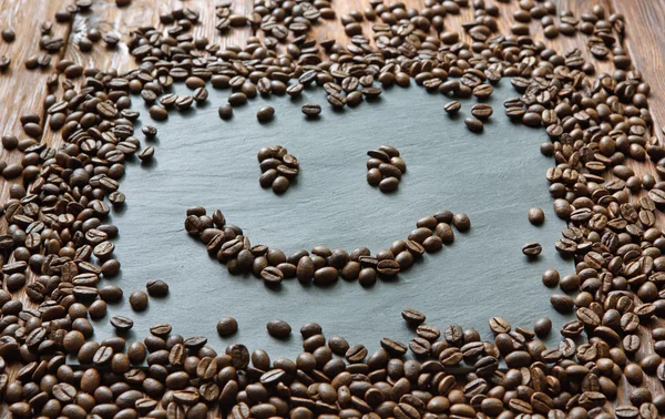 Smiley face from coffee beans at stone background — Stock Photo, Image