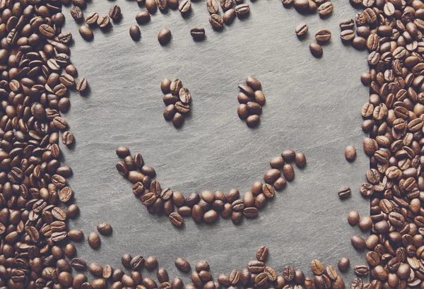Rosto sorridente de grãos de café no fundo de pedra — Fotografia de Stock