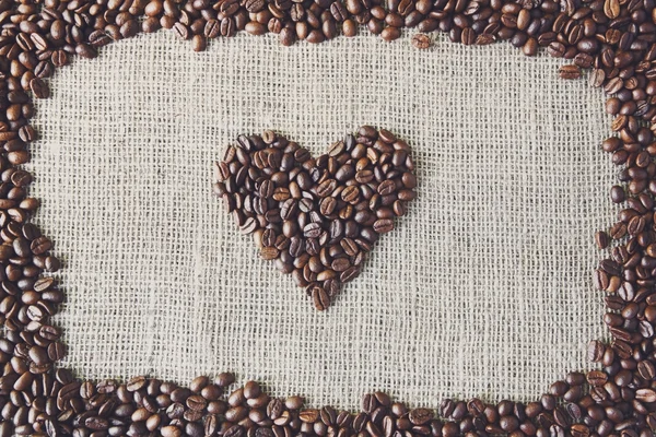 Texture di iuta con chicchi di caffè a forma di cuore — Foto Stock