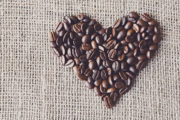 Texture di iuta con chicchi di caffè a forma di cuore — Foto Stock