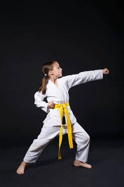 Bambino ragazza in abito da karate con cintura gialla mostra posizione — Foto Stock