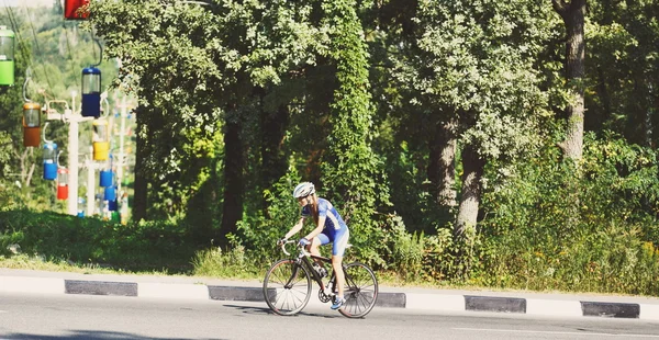 Mujer ciclista monta una bicicleta de carreras en la carretera —  Fotos de Stock