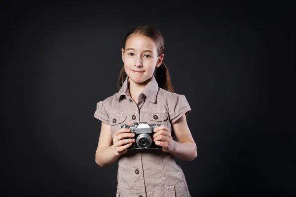 Маленька дівчинка фотографується з старовинною камерою на чорному тлі — стокове фото