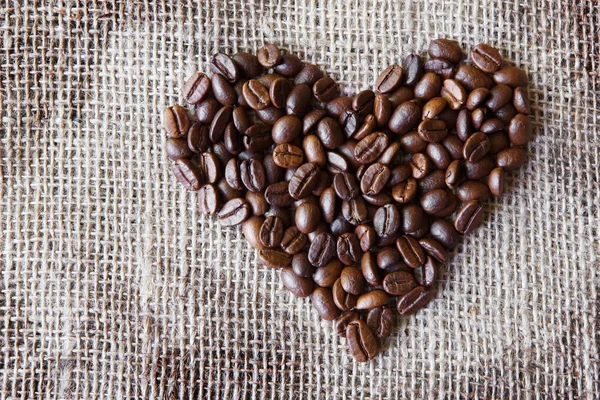 Texture di iuta con chicchi di caffè a forma di cuore — Foto Stock