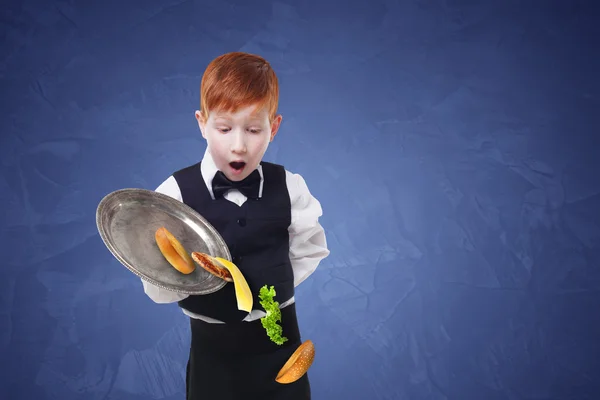 Tollpatschiger kleiner Kellner lässt Essen vom Tablett fallen, während er Hamburger serviert — Stockfoto