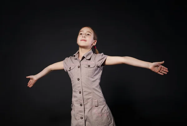 Menina pequena abre as mãos em gesto de mosca no fundo preto — Fotografia de Stock