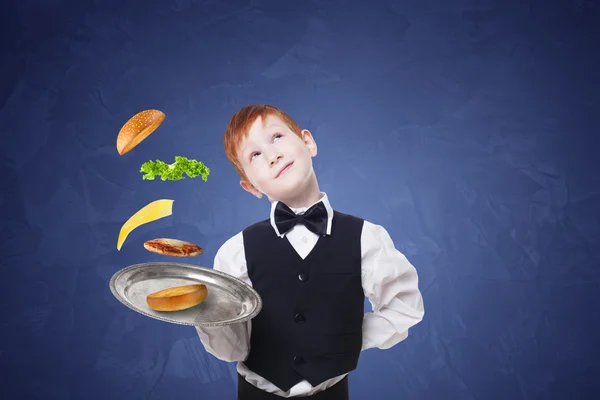 Маленький официант стоит с подносом, подающим гамбургеры отдельно летающие начинки — стоковое фото