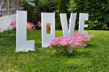 Aşk kelimesi dışarıda. Çimenler üzerinde büyük beyaz plastik harfler