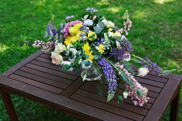 屋外の美しい花の花束。結婚式の木製テーブルで花の装飾 — ストック写真