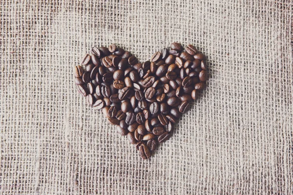 Burlap texture with coffee beans heart shape — Stock Photo, Image