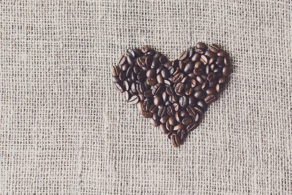 Texture di iuta con chicchi di caffè a forma di cuore — Foto Stock