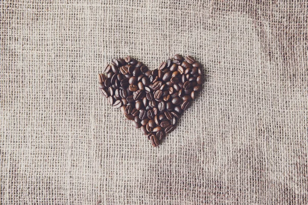 Бурлап текстуры с кофейных зерен форме сердца — стоковое фото