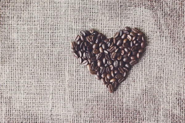 Texture di iuta con chicchi di caffè a forma di cuore — Foto Stock