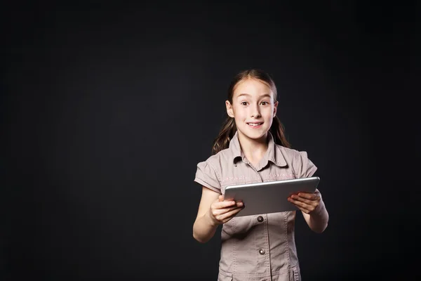 Bambina con tavoletta digitale su sfondo nero — Foto Stock