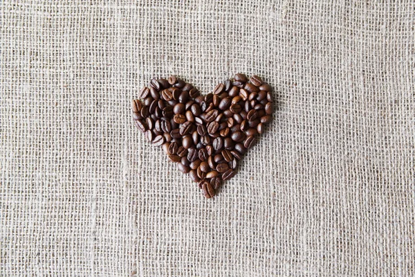 Бурлап текстуры с кофейных зерен форме сердца — стоковое фото