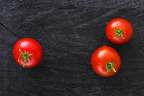 Tomates cerises rouges sur fond de bois rustique noir — Photo
