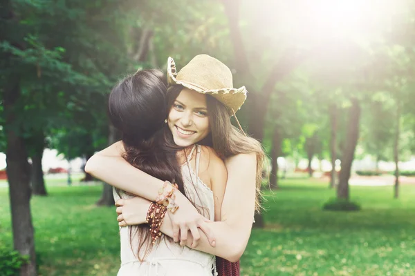 Дві щасливі молоді дівчата обіймаються в літньому парку — стокове фото