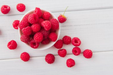 Beyaz rustik ahşap arka plan üzerinde kırmızı taze frambuaz