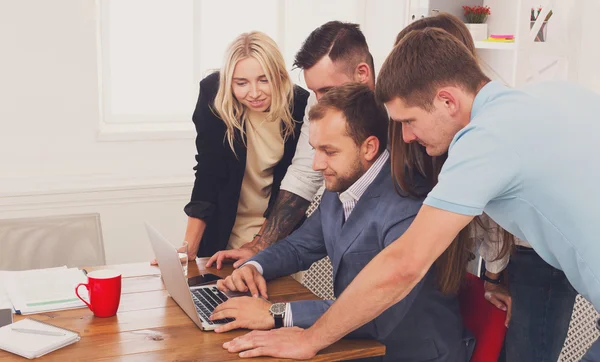 Feliz equipo de gente de negocios juntos mirar a la computadora portátil en la oficina — Foto de Stock