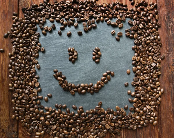 Rosto sorridente de grãos de café no fundo de pedra — Fotografia de Stock