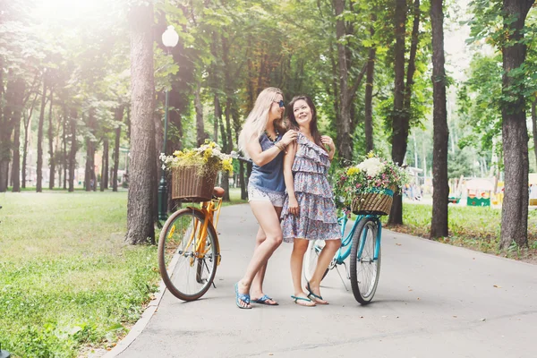 Boldog boho sikkes lányok együtt lovagolni kerékpárok park — Stock Fotó