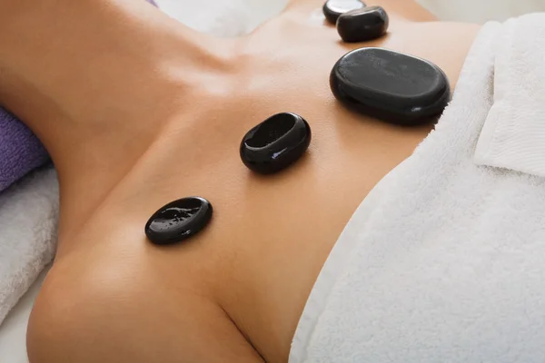 Kvinnan kropp närbild på stone massage spa i hälsocenter — Stockfoto